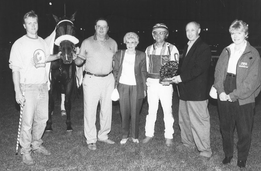 Armbro Leader appears in the winner’s circle. From left – groom Mike Keeling, A L, Wm. Wellwood, Jean Wellwood, Driver Bill O’Donnell, presenter, and on the far right Paula Wellwood Keeling.